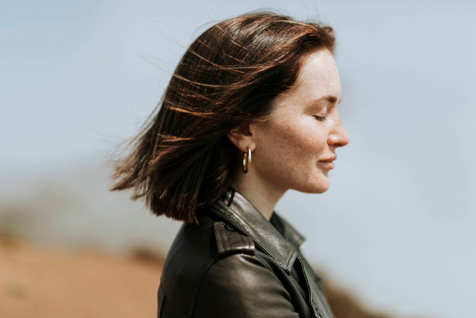side view of a woman in leather jacket standing in a park