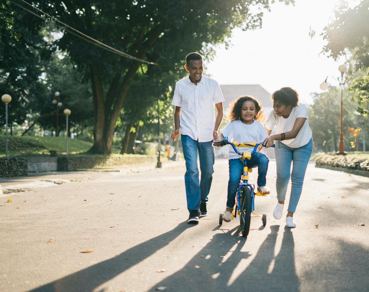 Home Happy family teaching their child to cycle on a sunny day outdoors.